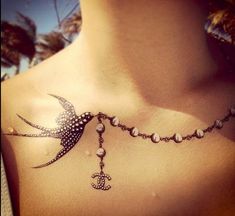 a woman's chest with a bird and anchor tattoo on it