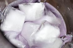 ice cubes in a blender filled with water and purple liquid on the side