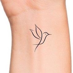 a small tattoo on the wrist of a woman with a bird flying above her arm