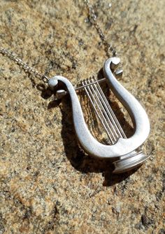 a silver necklace with a musical instrument on it's side sitting on a rock