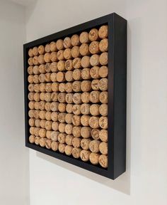 a wall mounted wine cork display in a room with white walls and black framed artwork