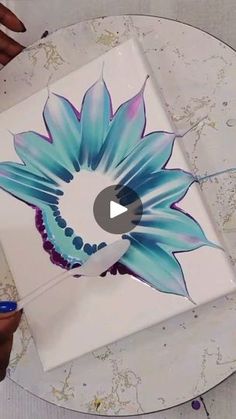 someone is painting a flower on the side of a white box with blue and purple flowers