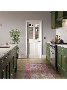 a kitchen with green cabinets and an area rug in front of the door that leads to another room