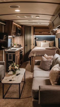 the interior of a motor home with couches, coffee table and kitchen in it