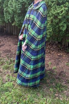 Cozy up with this warm cover. Great for game day, hay rack rides, bonfires or cuddling up. Winter cloak made of washable polyester blend. Has a 4 inch blue/green plaid. Revisable with a green soft brushed polyester fabric. Seams have been beautifully matched through out cloak. No size marked. One size fits most . Finished length is 50 inches neck to hem. Gently used and loved. Oversized Green Cape For Fall, Green Cape Outerwear For Fall, Green Cape For Fall, Oversized Green Cape For Winter, Green Fall Cape Outerwear, Winter Green Hooded Poncho, Green Cloak Aesthetic, Cozy Multicolor Winter Cape, Green Winter Cape Outerwear