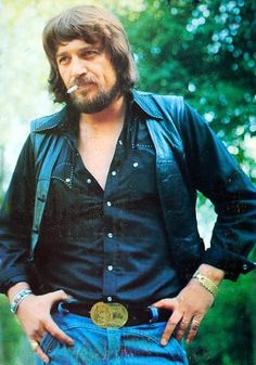 a man with his hands in his pockets wearing blue jeans and a black leather jacket