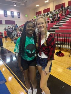 two girls standing next to each other in front of a gym filled with people and fans