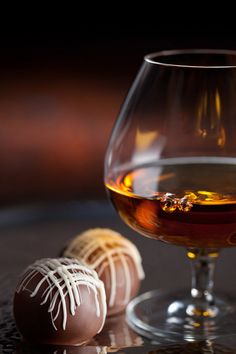 a glass of wine and some chocolates on a table with a woman's face in the background