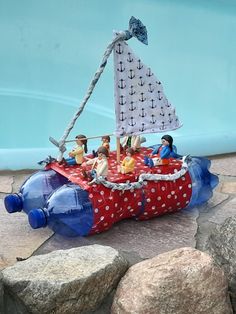 a boat made out of plastic bottles sitting on top of rocks next to a pool