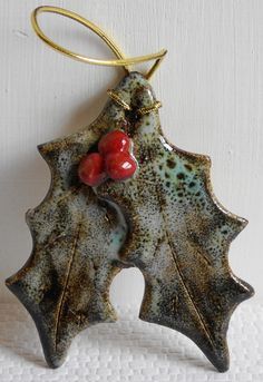 a ceramic leaf ornament with two cherries hanging from it's side