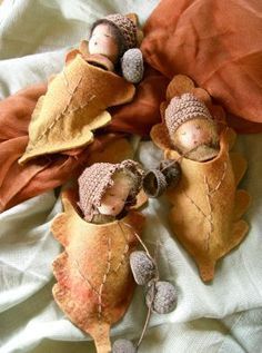 three little dolls are laying on some leaves