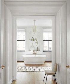 a white bathroom with a tub and chair in it