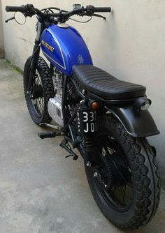 a blue and black motorcycle parked next to a white wall with the number 3 on it