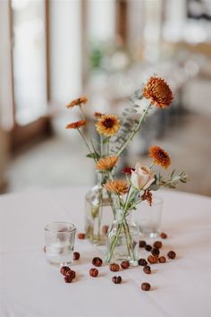 three vases filled with flowers sitting on top of a white table covered in coffee beans