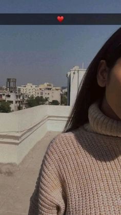 a woman standing on top of a roof with buildings in the background and a red heart above her head