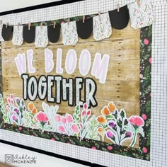 a wooden sign that says we bloom together with flowers on the front and back side