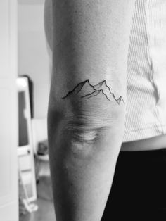 a man's arm with a mountain tattoo on it