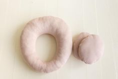 two pink donuts sitting next to each other on a white surface with wood flooring