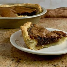 a piece of pie sitting on top of a white plate next to another pie dish