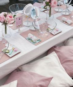 the table is set with pink and white flowers in vases, plates and napkins