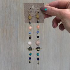 "handmade from solid brass Fishhook earring with Silicone push back closure. Earrings Hang approx. 4.5\" long. Crystal planets include: Mercury- hematite Venus- rhodonite or rhodochrosite Earth- sodalite, chrysocolla Mars- jasper Jupiter- agate Saturn - rainbow malachite, aura druzy Uranus- amazonite, howlite Neptune- howlite, quartzite Pluto - labradorite All metals used by Pop & Locket are nickel free and hypoallergenic. Steel wool works wonders for extra shine for a lifetime of wear. Each Celestial Nickel-free Earrings, Celestial Nickel-free Adjustable Earrings, Adjustable Celestial Nickel-free Earrings, Nickel-free Adjustable Space-themed Jewelry, Celestial Wire Wrapped Dangle Earrings, Adjustable Celestial Drop Earrings, Handmade Space-themed Dangle Jewelry, Celestial Dangle Crystal Earrings, Crystal Planet