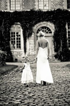 a mother and daughter walking in front of an old building