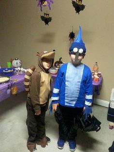 two children in costumes standing next to each other at a table with decorations on it