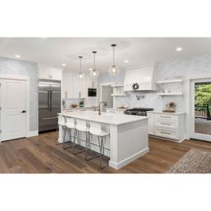 a large kitchen with white cabinets and stainless steel appliances, along with an island in the middle