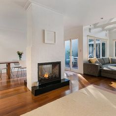 a living room filled with furniture and a fire place in the middle of a wooden floor