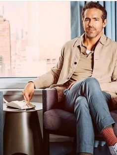 a man sitting in a chair next to a window with his feet on the table