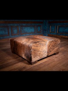 a leather ottoman sitting on top of a hard wood floor next to a blue wall