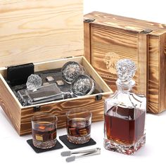 a wooden box with two glasses and a bottle in it next to a pair of razors