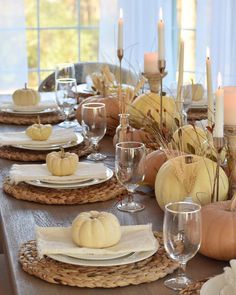 a table set for thanksgiving dinner with pumpkins and candles