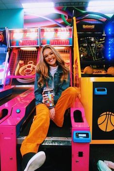 a woman sitting on top of a pink and yellow machine with basketball hoops in the background