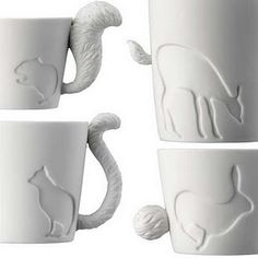 three white mugs with cats on them and one has a cat's tail