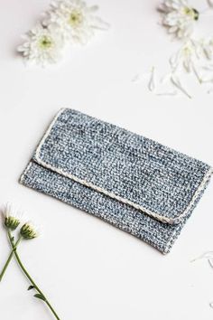 a small blue purse sitting on top of a white table next to some daisies