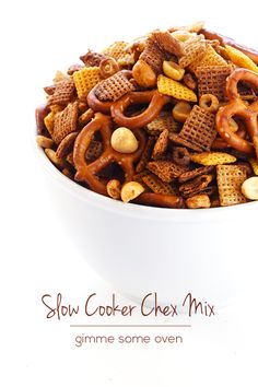 a bowl filled with cereal and pretzels on top of a white table next to the words slow cooker chex mix