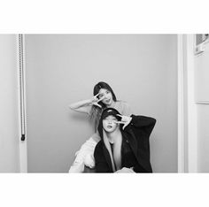 two young women sitting on the floor in front of a door and one is brushing her hair