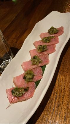 a white plate topped with meat and veggies on top of a wooden table