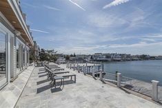 a row of benches sitting on the side of a building next to a body of water