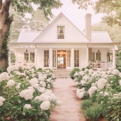 a white house surrounded by flowers and trees