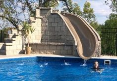 a man is swimming in a pool with a slide