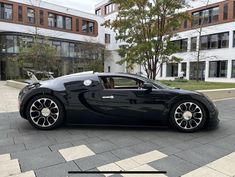 a black bugatti is parked in front of a large building with many windows