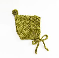 a green knitted hat with a knot tied around the front and side, on a white background