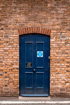 a brick building with a blue door and sign on it