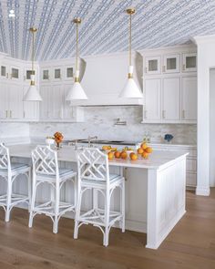 a kitchen with white cabinets and countertops has blue patterned ceiling tiles on the walls