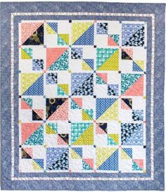 a blue and white quilt with multicolored triangles on the front, along with an embroidered border