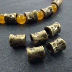 three pieces of brass with yellow beads on a table next to it's clasp