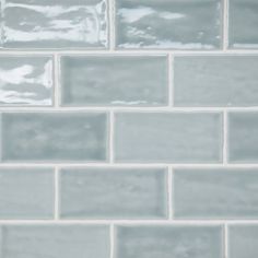 a close up view of a white tile wall with gray grouting on it