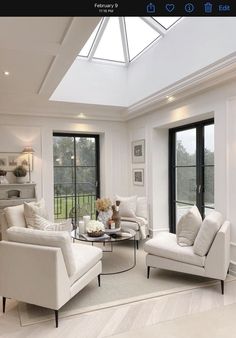 a living room filled with white furniture and windows covered in glass roofing over a wooden floor